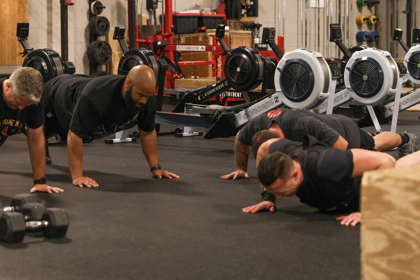 Three men mid push-up on the gym floor