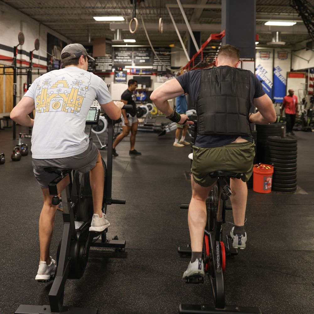 Two men riding air bikes during the workout
